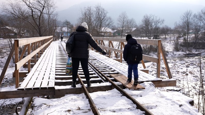 Жителька Нового Мізуня переводить сина через вузькоколійний міст.
